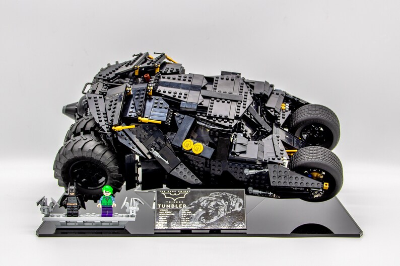 May include: A black LEGO The Dark Knight Tumbler model with a black and gold display stand. The model includes two minifigures: Batman and The Joker.