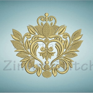 Może przedstawiać: Złoty haft przedstawiający stylizowane serce otoczone skomplikowanymi wzorami kwiatowymi. Projekt ma vintage'owy, ozdobny charakter.