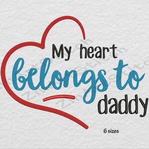 May include: Red heart with the text "My heart belongs to daddy" in blue and black lettering.  The text "6 sizes" is below the heart.