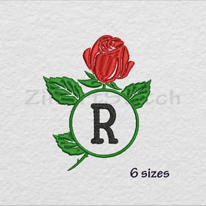 Könnte beinhalten: Stickerei einer roten Rose mit grünen Blättern, die einen Kreis mit dem Buchstaben "R" in Schwarz umgeben.