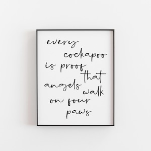 May include: A framed print with the text "every cockapoo is proof that angels walk on four paws" in black script on a white background. The frame is black and the print is centered.