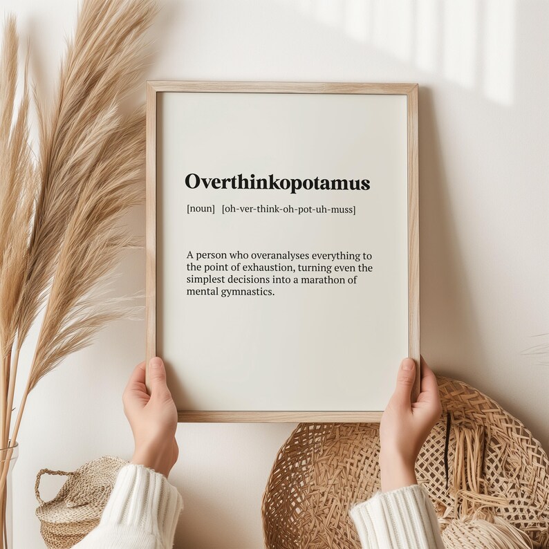 May include: A framed print with a white background and black text defining the word "Overthinkopotamus" as a noun, meaning "a person who overanalyses everything to the point of exhaustion, turning even the simplest decisions into a marathon of mental gymnastics."