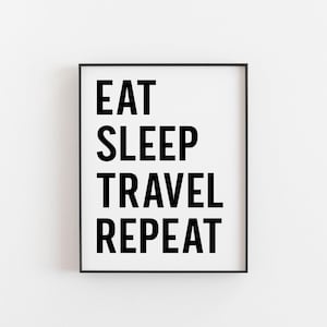 May include: Black and white framed print with the text "Eat Sleep Travel Repeat" in bold letters.