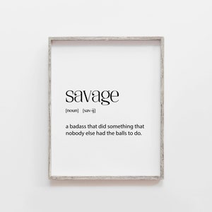 May include: A framed print with a white background and black text that reads "savage" with the definition "a badass that did something that nobody else had the balls to do."
