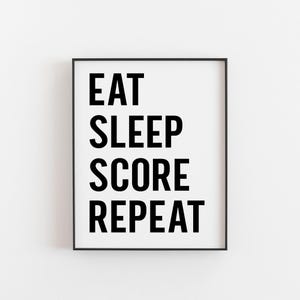 Könnte beinhalten: Schwarz-weiß gerahmter Druck mit dem Text "Eat Sleep Score Repeat" in fetten Großbuchstaben.