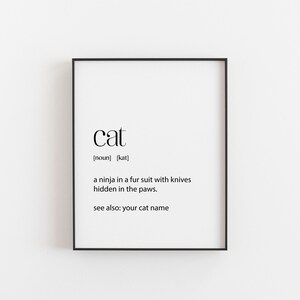 May include: Black and white typography print with the word "cat" defined as "a ninja in a fur suit with knives hidden in the paws. See also: your cat name."