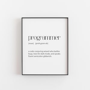 May include: A black framed print featuring the word "programmer" in a modern font. The definition below reads: "a code-conjuring wizard who battles bugs, lives for dark mode, and speaks fluent semicolon gibberish."