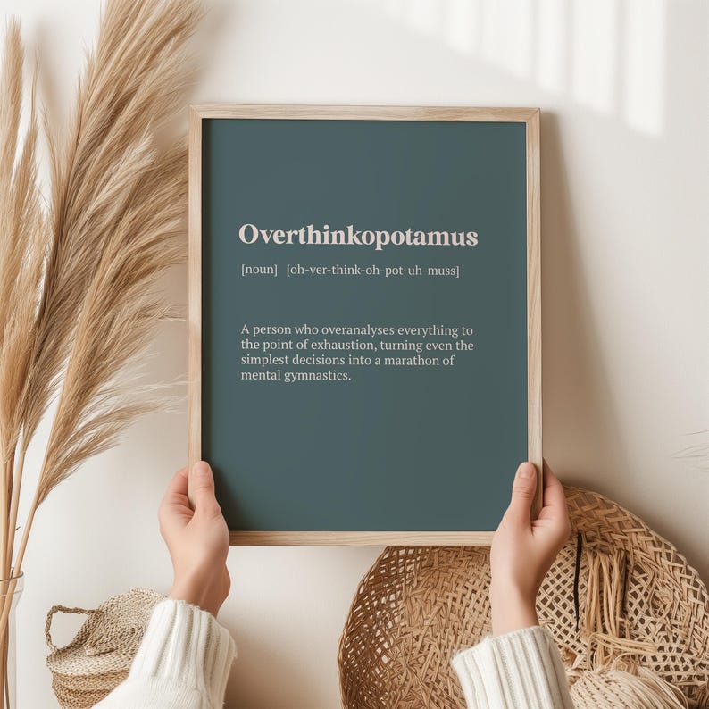 May include: A teal framed print with the word "Overthinkopotamus" defined as "a person who overanalyses everything to the point of exhaustion, turning even the simplest decisions into a marathon of mental gymnastics."