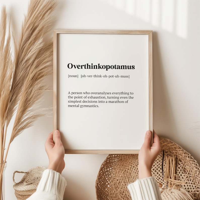 May include: A framed print with a white background and black text defining the word "Overthinkopotamus" as a noun, meaning "a person who overanalyses everything to the point of exhaustion, turning even the simplest decisions into a marathon of mental gymnastics."