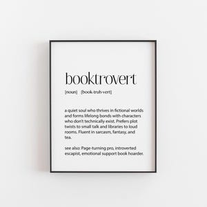 May include: Black and white printable wall art with the definition of the word "booktrovert". The definition describes a person who enjoys fictional worlds and characters, prefers reading to socialising, and enjoys sarcasm, fantasy, and tea.
