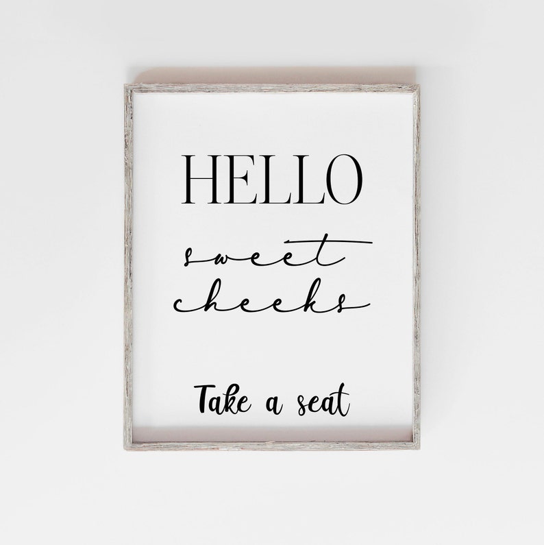 Może przedstawiać: Wydruk w ramie z tekstem "HELLO sweet cheeks Take a seat" w czarnym kolorze na białym tle.