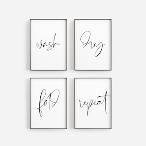 May include: Four framed prints with black frames and white backgrounds. Each print features a single word in elegant black script: "wash", "dry", "fold", and "repeat". These prints are designed for a laundry room.
