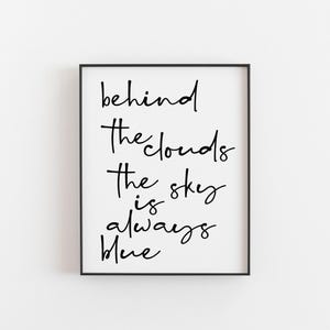 Op de afbeelding: Zwart-wit typografieprint met de quote "Achter de wolken is de lucht altijd blauw".
