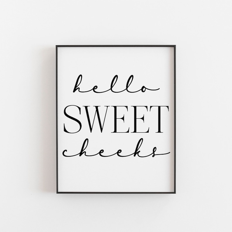 Op de afbeelding: Zwart-witte ingelijste print met de tekst "hello sweet cheeks" in een cursief lettertype.