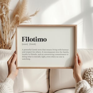 May include: A framed print with the word "Filotimo" in bold black letters. The definition of the Greek term is below the word, in a simple, elegant font. The frame is a light brown color.