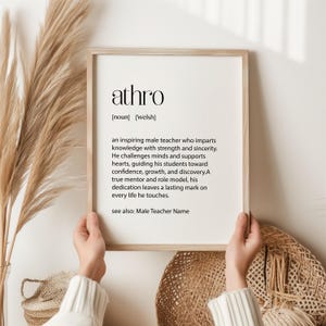 May include: A framed print with the word "athro" at the top, defined as an inspiring teacher. The definition is written in black text on a white background. The frame is a light wood color.