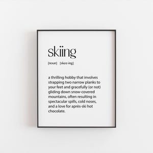 May include: Black and white printable art print with the definition of the word "skiing". The definition reads: "a thrilling hobby that involves strapping two narrow planks to your feet and gracefully (or not) gliding down snow-covered mountains, often resulting in spectacular spills, cold noses, and a love for après-ski hot chocolate."