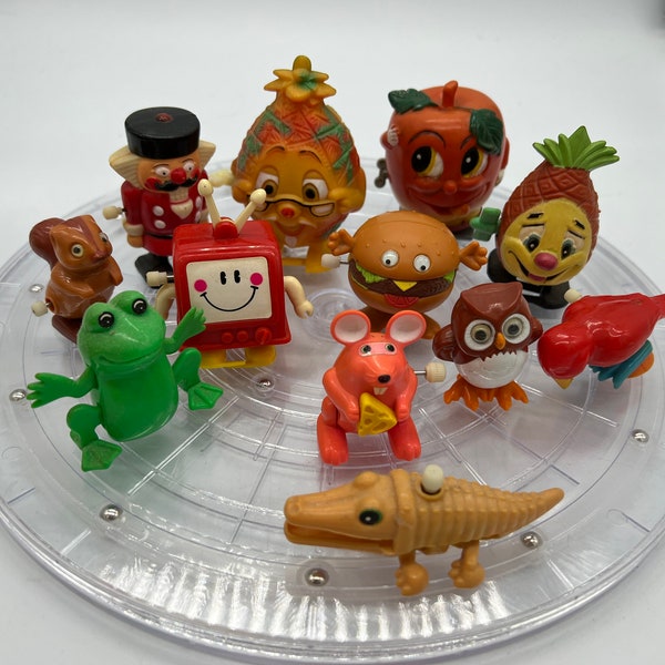Piña antropomorfa vintage, manzana, hamburguesa con queso, animales y televisión y más juguetes de cuerda. ¡Se vende por separado!