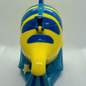 Puede incluir: Un juguete de pl&aacute;stico de pescado amarillo y azul con una aleta azul en la parte superior. El pez tiene un patr&oacute;n de rayas azules y amarillas y una estrella blanca en el lateral.