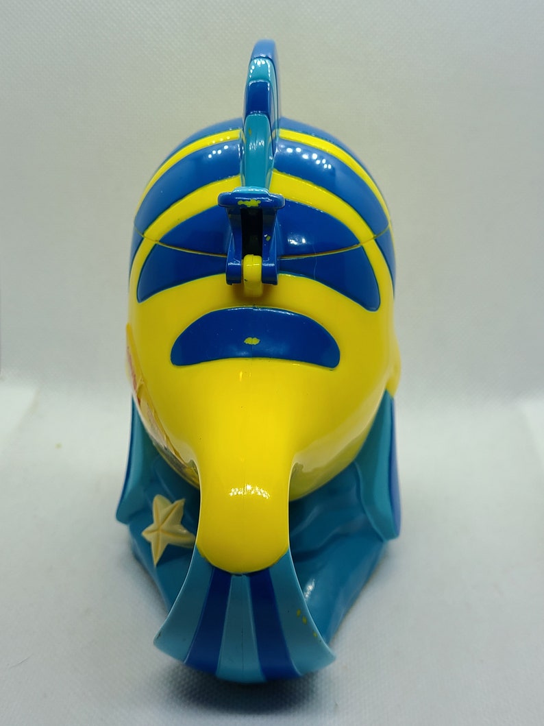 Puede incluir: Un juguete de pl&aacute;stico de pescado amarillo y azul con una aleta azul en la parte superior. El pez tiene un patr&oacute;n de rayas azules y amarillas y una estrella blanca en el lateral.