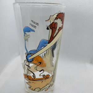 May include: A clear glass featuring a cartoon image of Wile E. Coyote chasing the Road Runner. The Road Runner is on a makeshift vehicle and the text "Beep! Beep!" is visible on the glass.