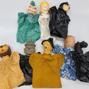 May include: A set of nine Wizard of Oz character hand puppets. The puppets are made of felt and plastic and feature characters like Dorothy, the Scarecrow, the Tin Man, the Cowardly Lion, the Wicked Witch of the West, and Glinda the Good Witch.