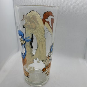 May include: A clear glass featuring a cartoon image of Wile E. Coyote and Road Runner. The glass has the Pepsi logo on the bottom.