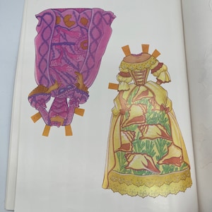 Puede incluir: Dos mu&ntilde;ecas de papel con atuendos diferentes. La primera mu&ntilde;eca lleva un vestido rosa y morado con un borde de encaje blanco. La segunda mu&ntilde;eca lleva un vestido amarillo con un patr&oacute;n de conchas marinas y hojas verdes.