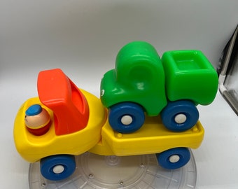 Camión clásico de plataforma plana Little Tikes de estilo vintage con un camión más pequeño.