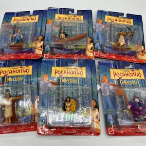 Può includere: Sei confezioni di plastica non aperte di figurine da collezione Disney Pocahontas. Ogni confezione presenta un personaggio diverso del film, tra cui Pocahontas, John Smith, Meeko e Percy. Le confezioni sono tutte rosse e bianche con il logo Disney e le parole "Pocahontas Collectible" stampate su di esse.