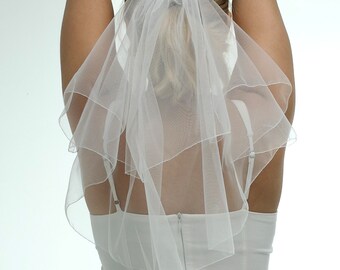 May include: A white single-tier bridal veil with a comb attachment. The veil is made of soft tulle and has a delicate, flowing design.