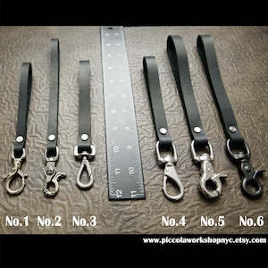 May include: A collection of six black leather keychains with various metal clasp styles. Each keychain has a loop and is attached to a metal clasp. A ruler is placed next to the keychains. The text "No.1" through "No.6" is visible.