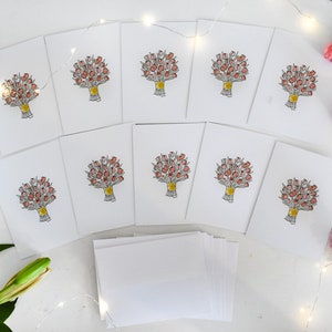 K&ouml;nnte beinhalten: Eine Sammlung wei&szlig;er Gru&szlig;karten, jede mit einer handgezeichneten Illustration eines Blumenstrau&szlig;es aus roten Blumen, der mit einem gelben Band gebunden ist. Die Karten sind auf einer wei&szlig;en Oberfl&auml;che angeordnet, mit zus&auml;tzlichen leeren Karten und floralen Akzenten.