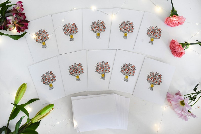 K&ouml;nnte beinhalten: Eine Sammlung wei&szlig;er Gru&szlig;karten, jede mit einer handgezeichneten Illustration eines Blumenstrau&szlig;es aus roten Blumen, der mit einem gelben Band gebunden ist. Die Karten sind auf einer wei&szlig;en Oberfl&auml;che angeordnet, mit zus&auml;tzlichen leeren Karten und floralen Akzenten.