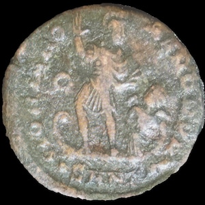 May include: A weathered, circular bronze coin with an embossed design. The coin features a standing figure with an arm raised, and a smaller figure at their feet. The coin's surface is aged with a dark green patina.