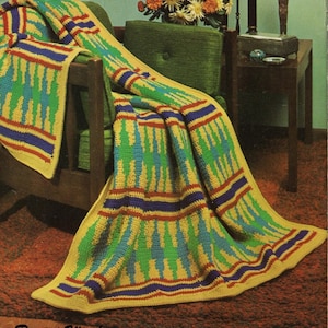 May include: A colorful crocheted blanket with a geometric pattern in shades of yellow, green, blue, and red. The blanket is draped over a green chair and features a repeating design of vertical lines and stripes.