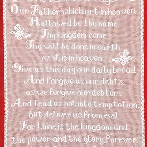 May include: White crocheted piece with the text of The Lord's Prayer, framed by a red border. The prayer is written in white script, with decorative cross and butterfly motifs. A traditional religious item.