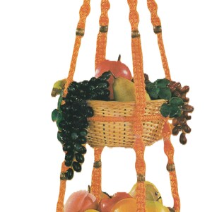May include: A three-tiered hanging fruit basket made of woven wicker with an orange rope design. The basket is filled with fruit, including apples, pears, grapes, and a banana.