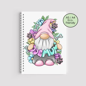 May include: A notebook with a spiral binding, showcasing a colourful illustration of a gnome with a pink hat and beard, surrounded by flowers and paw prints. The text "DOG MUM" is displayed. A green circle indicates the notebook is A5/A4 Eco-Friendly.