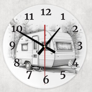 May include: A white round clock with black numbers and hands. The clock face features a black and white illustration of a vintage camper parked in a wooded area. The clock hands are set to 12:00.