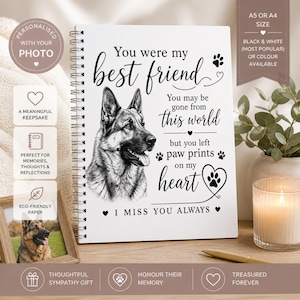 May include: A white spiral-bound notebook featuring a German Shepherd illustration and the words "You were my best friend." The text continues with "You may be gone from this world but you left paw prints on my heart." Available in A5 or A4 sizes.