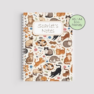 May include: A spiral-bound notebook with a cream-colored cover featuring a repeating pattern of various cat illustrations. The notebook has the text "Scarlet's Notes" on the cover. The notebook is labeled as A5/A4 Eco-Friendly.