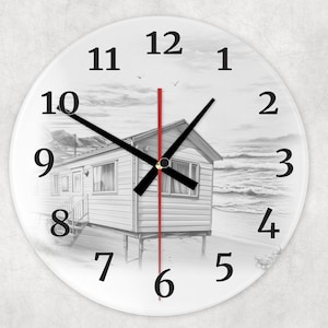 May include: Round wall clock with a beach scene illustration. The clock face features a black and white drawing of a beach house on the shore, with black clock hands and bold black numerals. A red second hand adds a pop of color.
