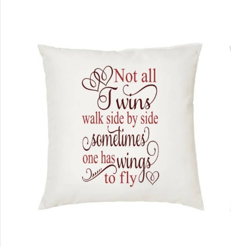 May include: A white square pillow with the text "Not all Twins walk side by side sometimes one has wings to fly" in a burgundy script font. The pillow has a heart design.