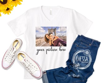 Op de afbeelding: Wit T-shirt met V-hals en een foto van een stel voor een brug. De tekst "your picture here" staat onder de foto.