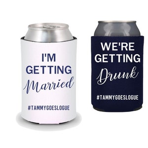 May include: Two white can coolers with blue text. One cooler says "I'm Getting Married" and the other says "We're Getting Drunk". Both coolers have the hashtag "#TAMMYGOESLOGUE" printed on them.