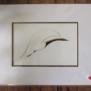 May include: A framed print of a black and gold stylised bird in flight. The print is on white paper and has a white mount. The print is signed by the artist, "Margaret West."