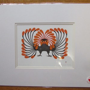 May include: A black and orange print of a stylised bird with a large, feathery crest. The bird is standing with its wings spread out. The print is framed and mounted.