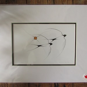 May include: A framed black and white print of three stylised birds in flight with a small orange circle in the centre. The print is titled "Manitoulin" and is signed by the artist.