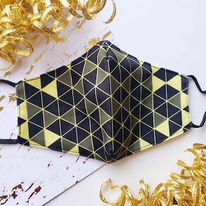 May include: A black and yellow geometric patterned face mask. The mask has a triangular pattern with black lines and yellow triangles.
